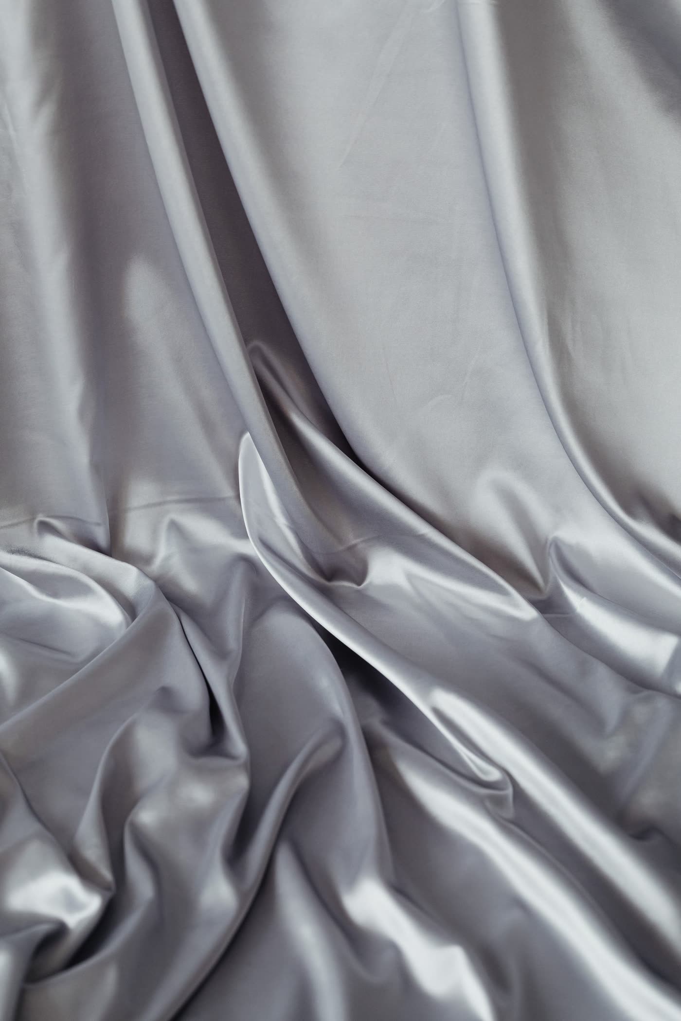 Close-up of rippled silver satin fabric, the kind used to line a casket interior
