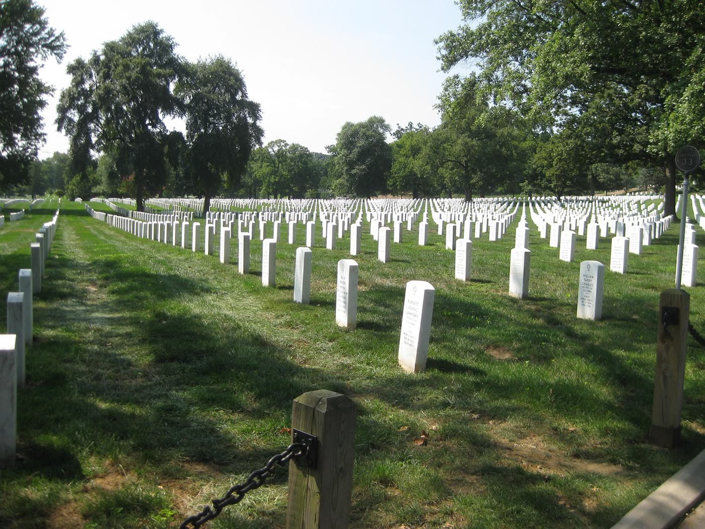 Rows of small white upright markers in a well-kept national cemetery lawn