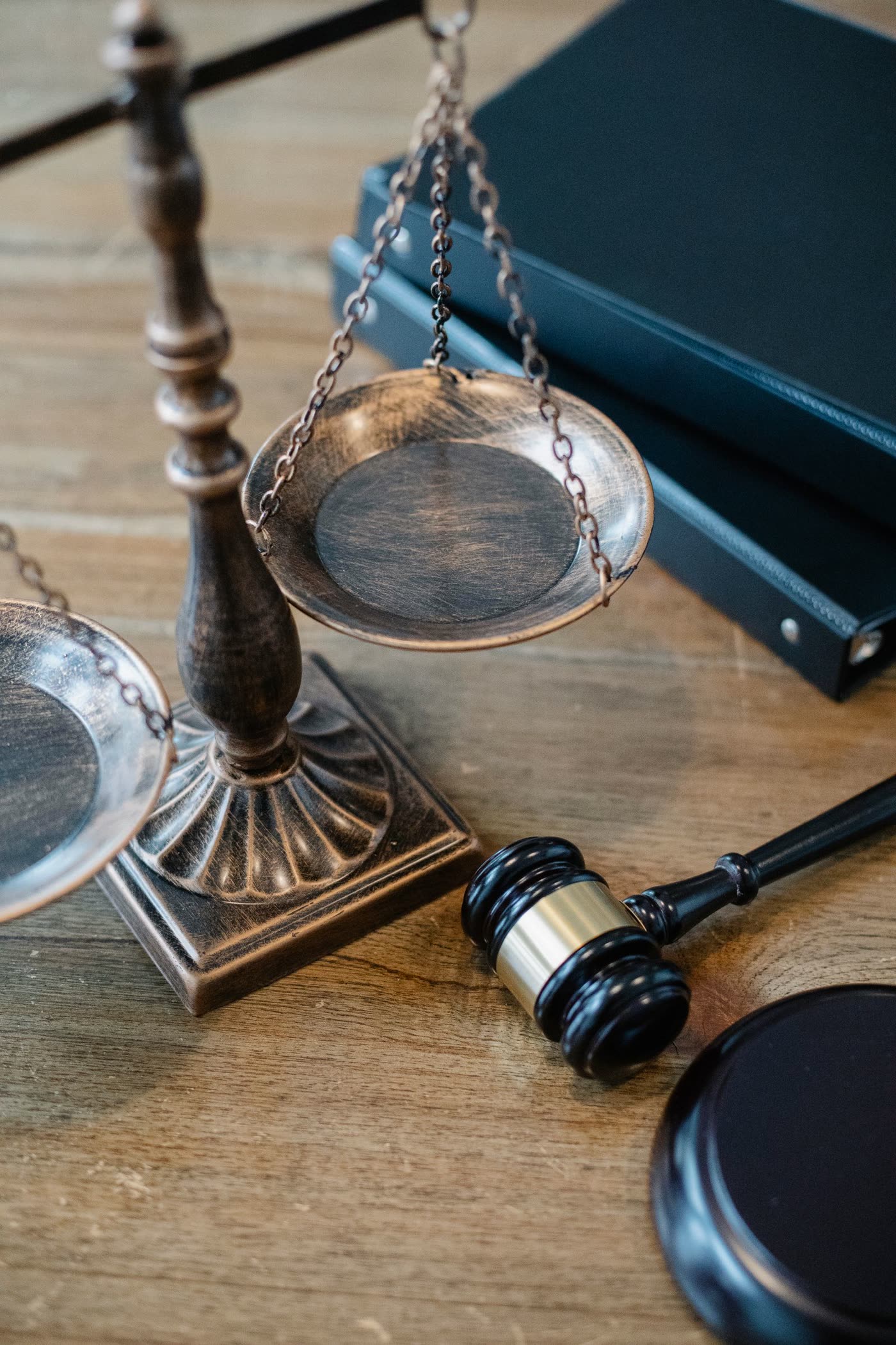 A close-up of a gavel and scales of justice on a wooden table beside legal books