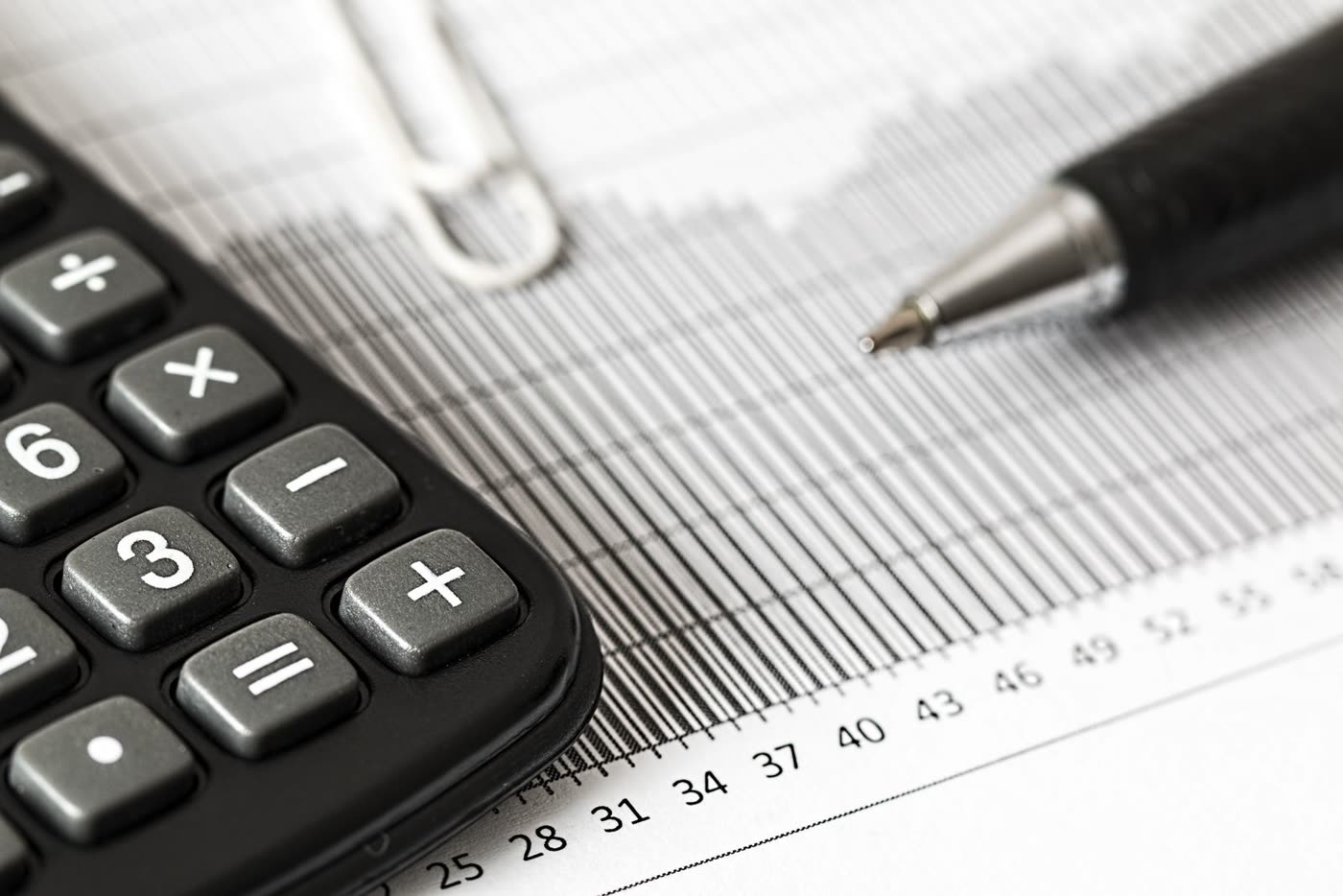 A calculator and pen resting on a printed bar graph